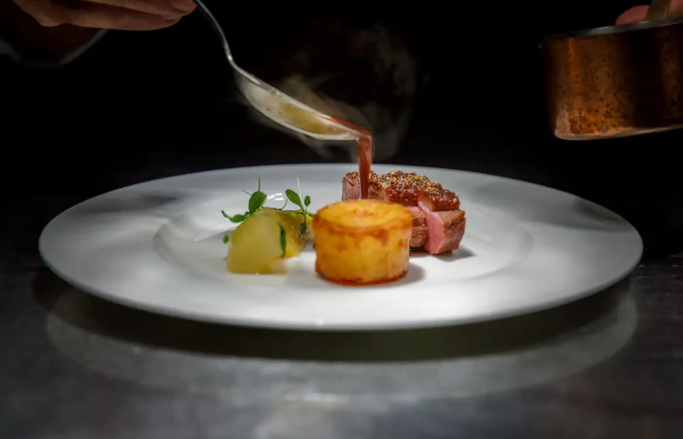 Lo chef completa un piatto con la salsa